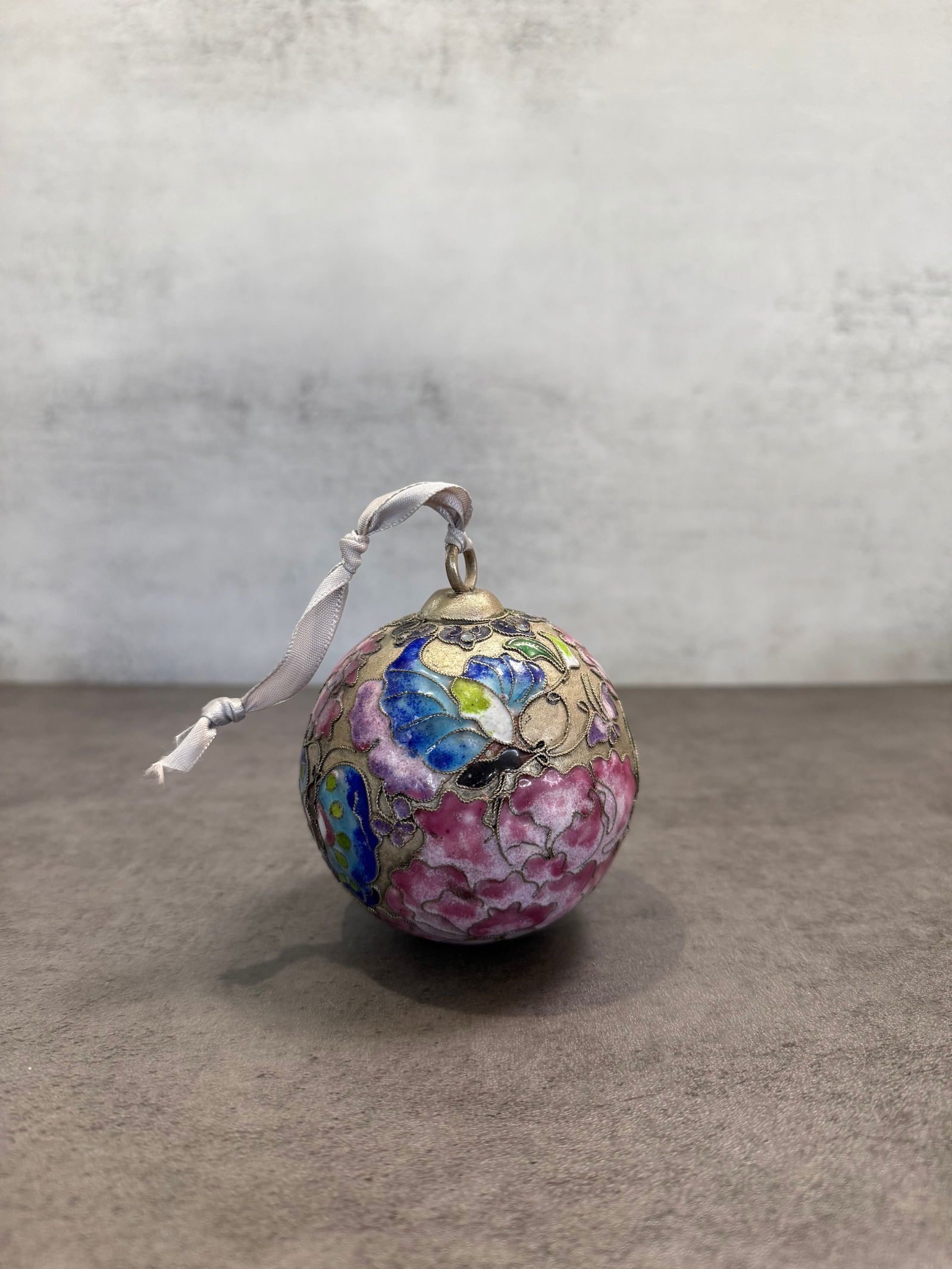 Chinese Cloisonné Enamel Ornament Ball – Floral & Butterfly Decorative Hanging Piece: A charming vintage Chinese cloisonné enamel ornament, featuring a spherical form adorned with vibrant floral and butterfly motifs.The piece is finely decorated with colorful enamel work set within
