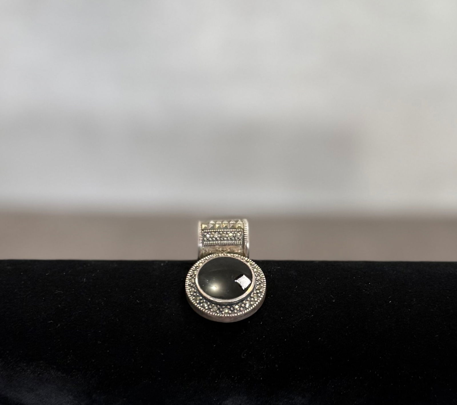 Vintage Sterling Silver Pendant with Black Cabochon Stone – Marcasite Style Jewelry: A refined vintage pendant crafted in silver, featuring a smooth black cabochon stone set within an ornate decorative frame.The design is accented with intricate detailing reminiscent of