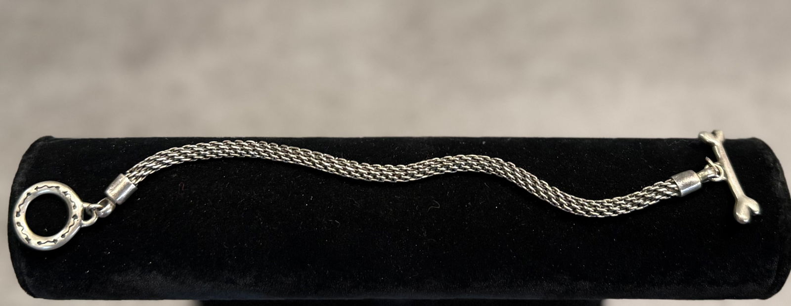 Vintage Sterling Silver Bracelet with Dog Bone Charm & Toggle Clasp – Braided Chain Design: A distinctive vintage sterling silver bracelet featuring a finely braided chain and a playful dog bone charm accent.The bracelet is fitted with a classic toggle clasp, offering both security and ease