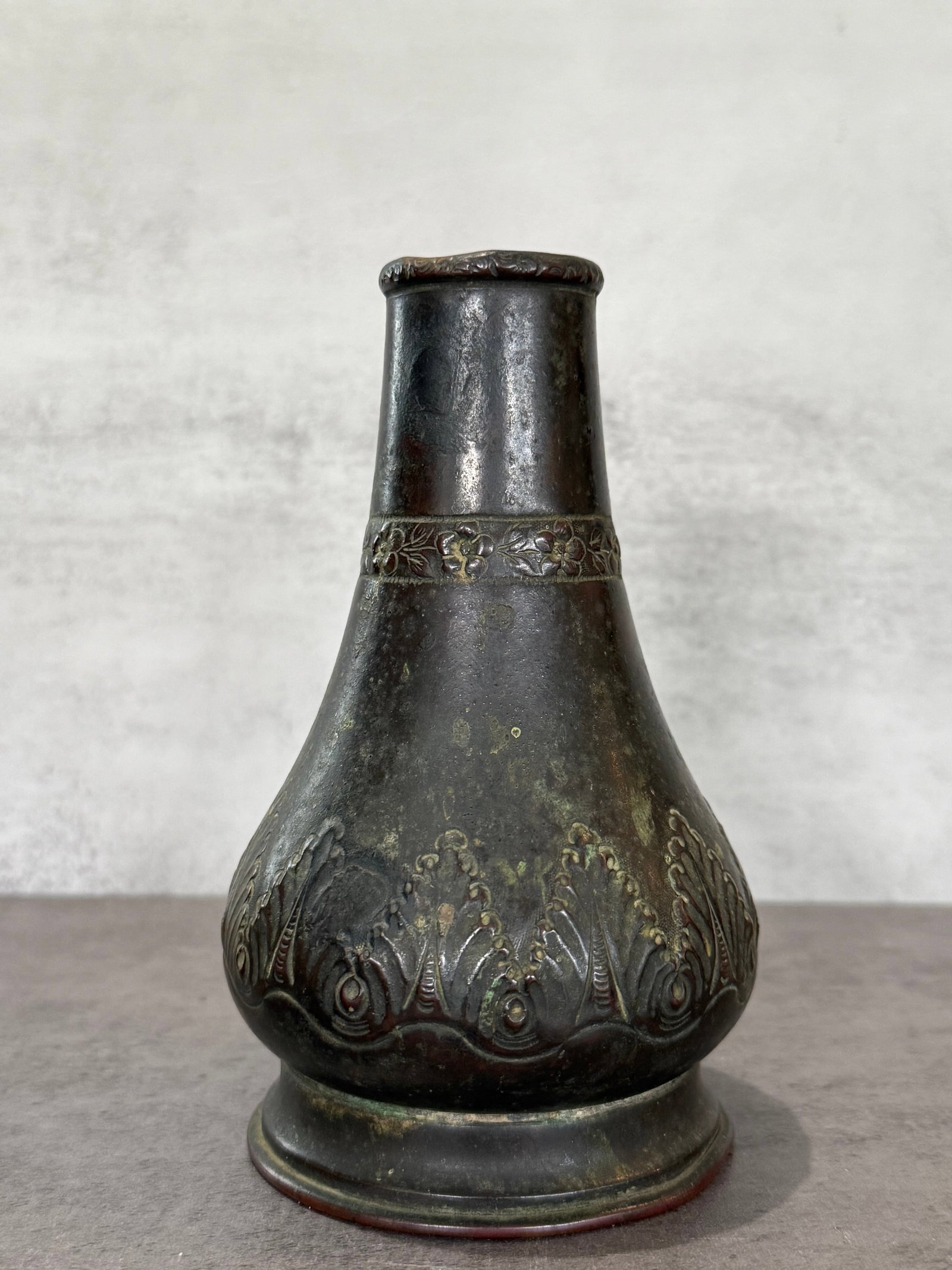 Asian Bronze Vase with Relief Floral Decoration: Asian bronze vase of baluster form featuring relief floral and scrolling decoration around the lower body and neck. The surface displays a dark aged patina with areas of verdigris and oxidation throug