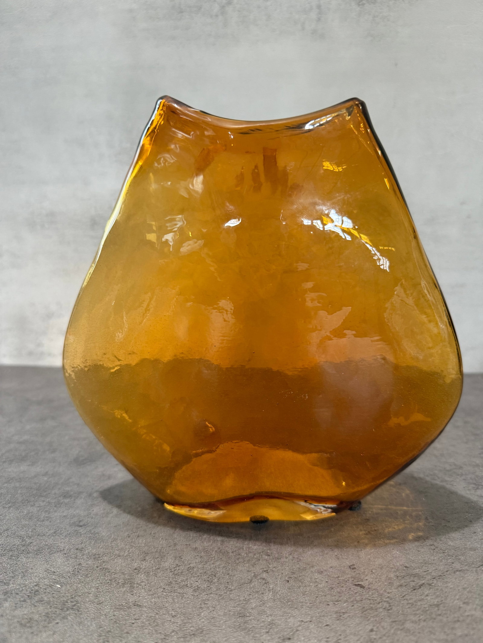 Handmade Amber Art Glass Freeform Vase: Handmade freeform art glass vase in a warm amber tone, featuring an organic asymmetrical rim and softly rounded bulbous form. Displays attractive translucency and fluid studio glass character.