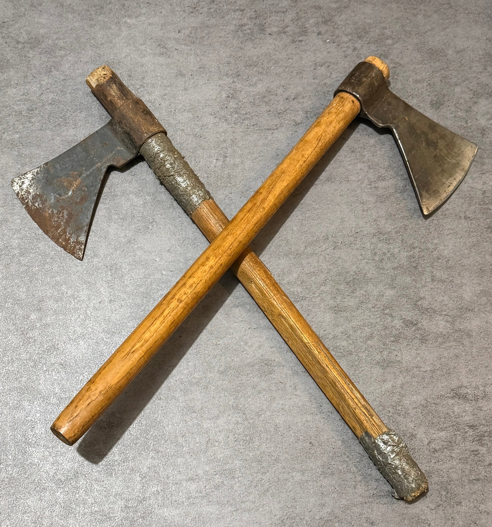 Pair of Antique Hand Forged Primitive Frontier Hatchets: A pair of antique hand forged primitive iron hatchets, dating to the late 19th to early 20th century. Featuring hand-worked iron heads mounted on wooden handles with rich aged patina and visible
