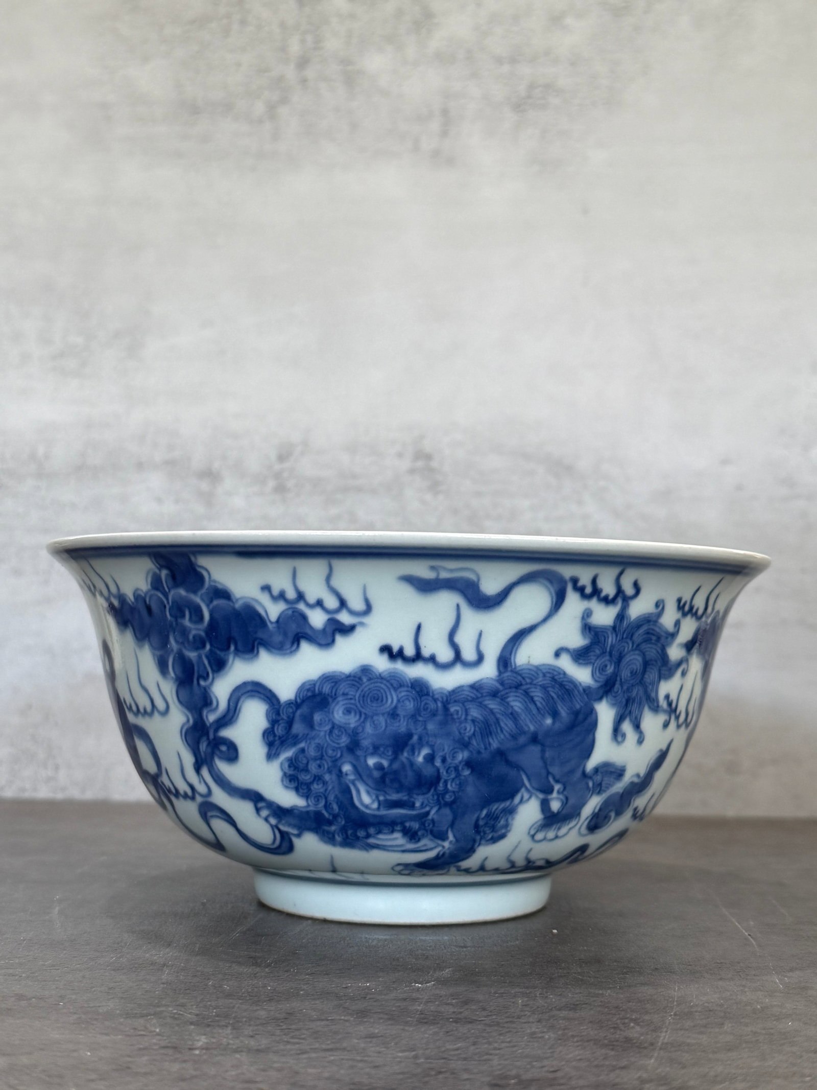 Chinese Blue and White Porcelain Bowl with Mythical Beast Decoration: A Chinese blue and white porcelain bowl, decorated in underglaze cobalt blue with scrolling clouds and mythical beast motifs. The exterior features a vividly painted stylized Buddhist lion or