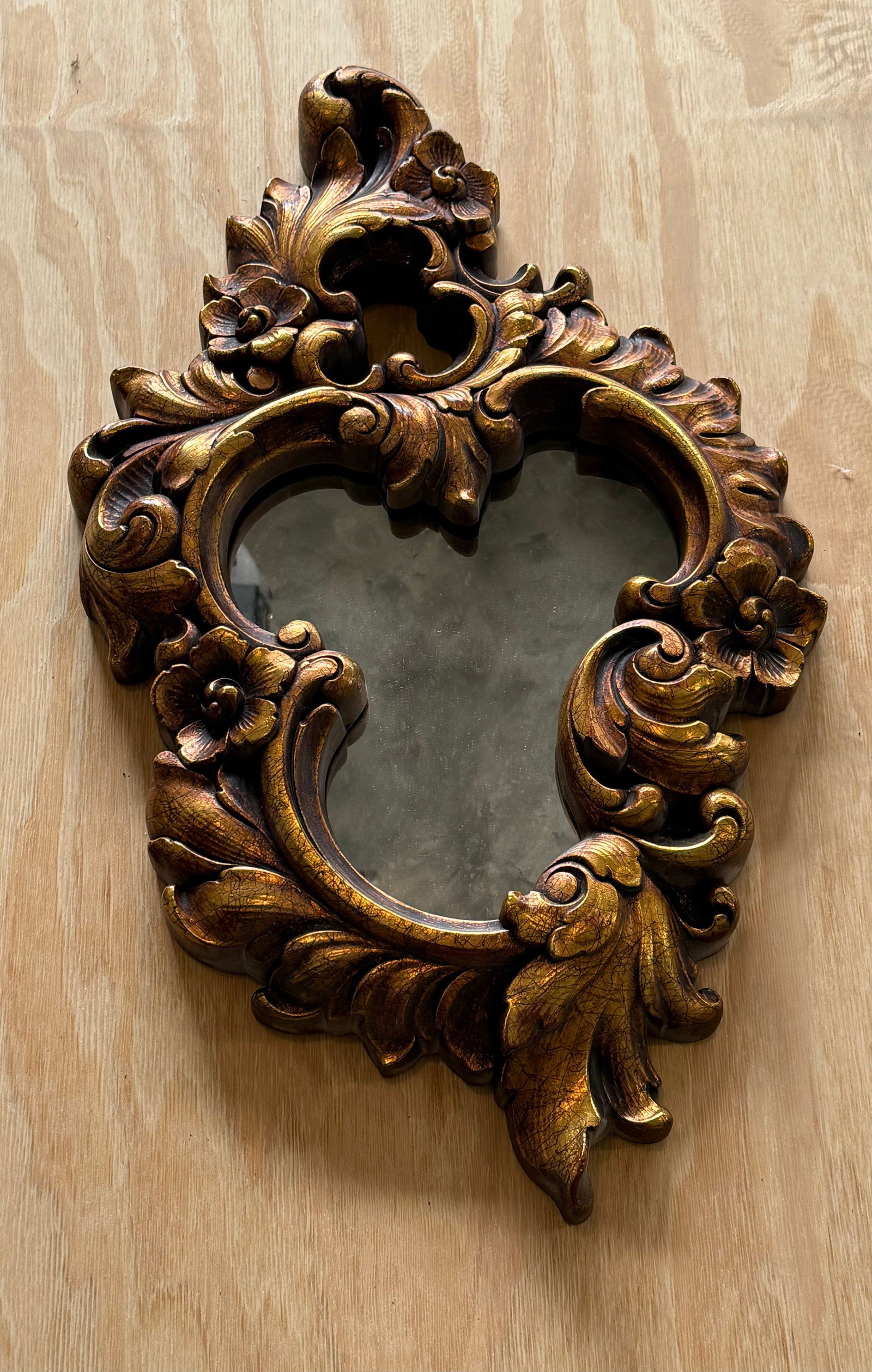 Carved Wooden Rococo Style Wall Mirror: An ornate carved wooden wall mirror in Rococo taste, featuring elaborate scrolling acanthus leaf and floral motifs throughout the frame. The asymmetrical silhouette and richly molded decoration give
