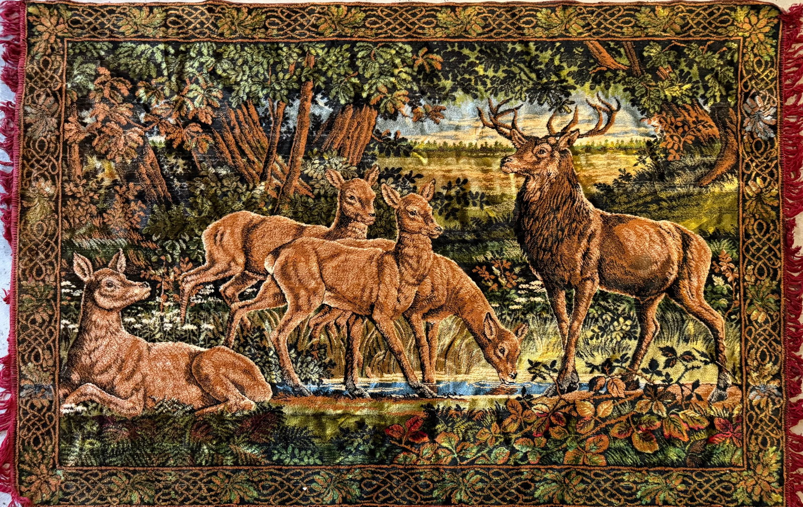 Vintage European Style Deer Scene Woven Tapestry Wall Hanging: Vintage woven tapestry wall hanging depicting a woodland deer scene with stag, does, and fawns gathered beside a stream within a richly detailed forest landscape. Executed in warm earth tones with
