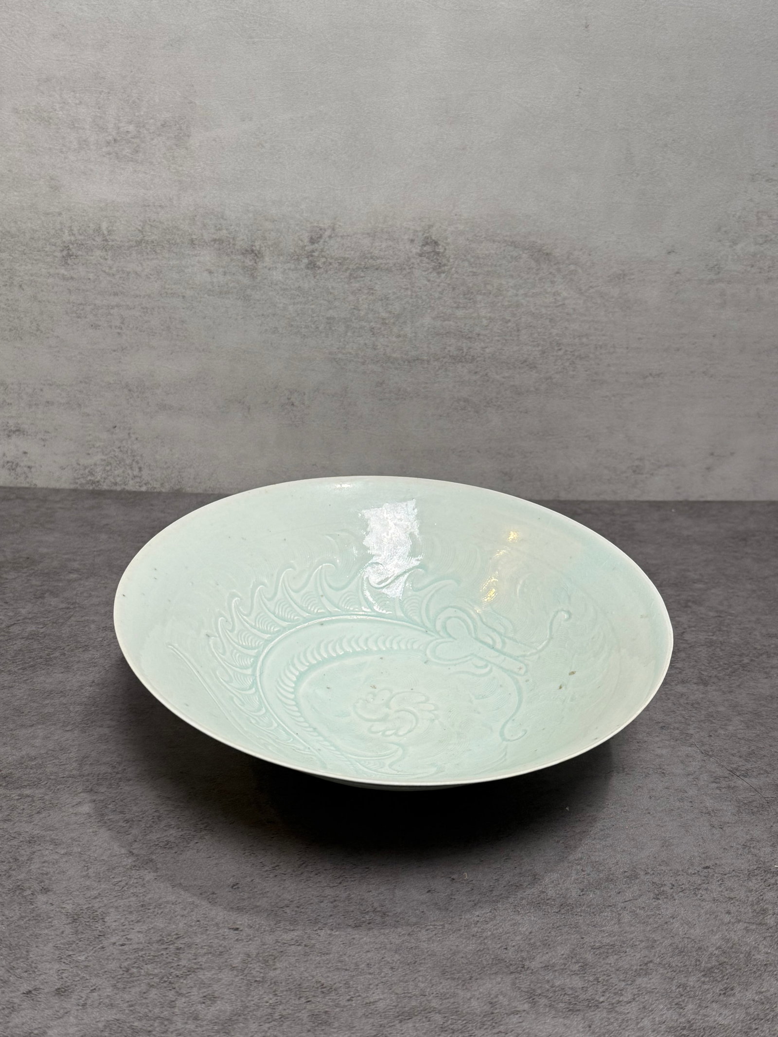 Chinese Qingbai Glaze Carved Porcelain Bowl: Chinese Qingbai glaze porcelain bowl featuring a delicately carved interior decoration beneath a soft bluish-white translucent glaze. The shallow rounded form displays elegant molded ornamentation