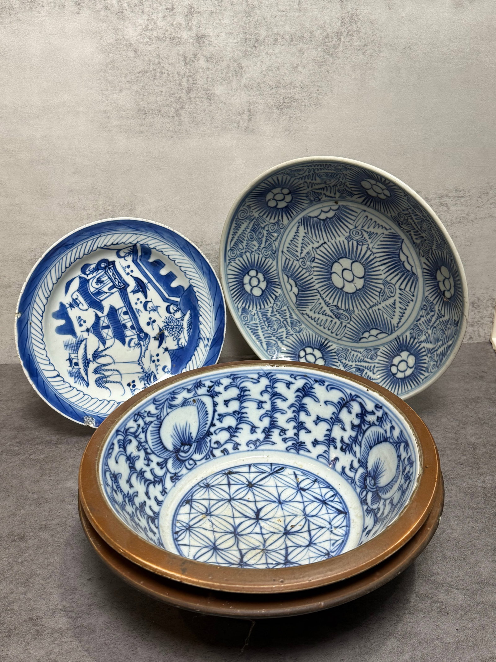 GROUP OF BLUE AND WHITE PORCELAIN BOWLS & PLATES: A group of blue and white porcelain table wares, including two shallow bowls and two plates, each decorated with stylized floral, geometric, and scenic motifs in underglaze cobalt blue. The