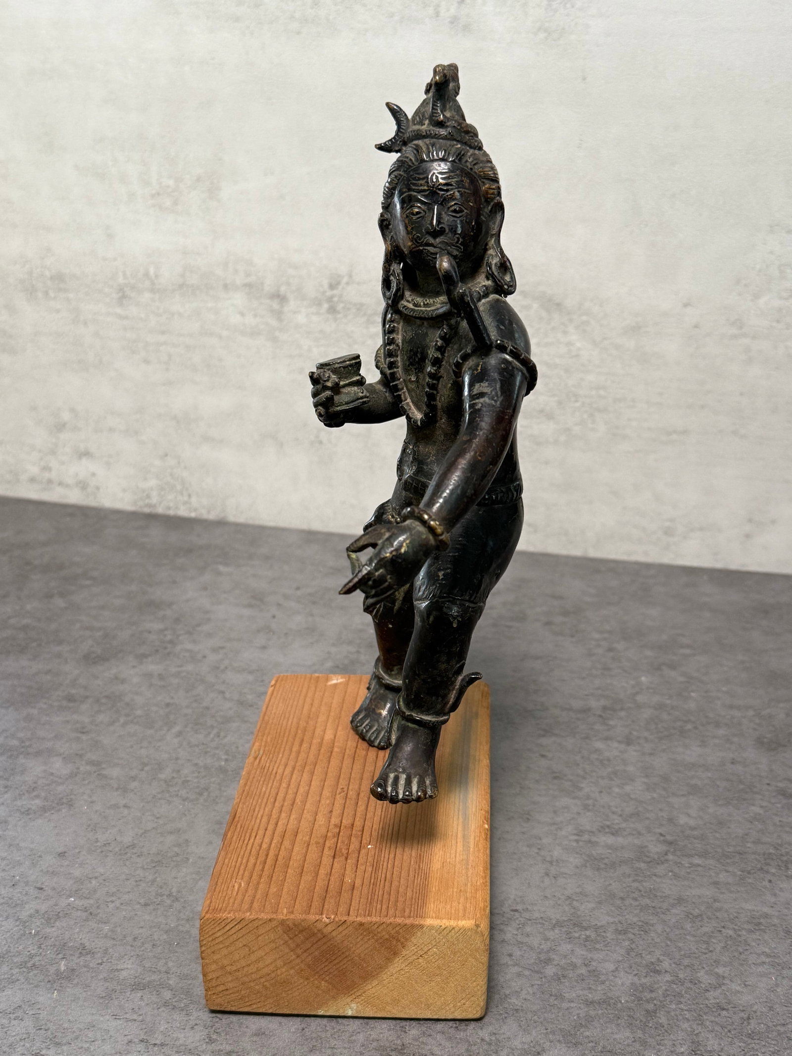 BRONZE FIGURAL SCULPTURE OF A DANCING DEITY: A bronze figural sculpture depicting a dynamic standing deity or ritual figure in animated posture, adorned with jewelry, headdress, and expressive facial detailing. The figure is shown holding