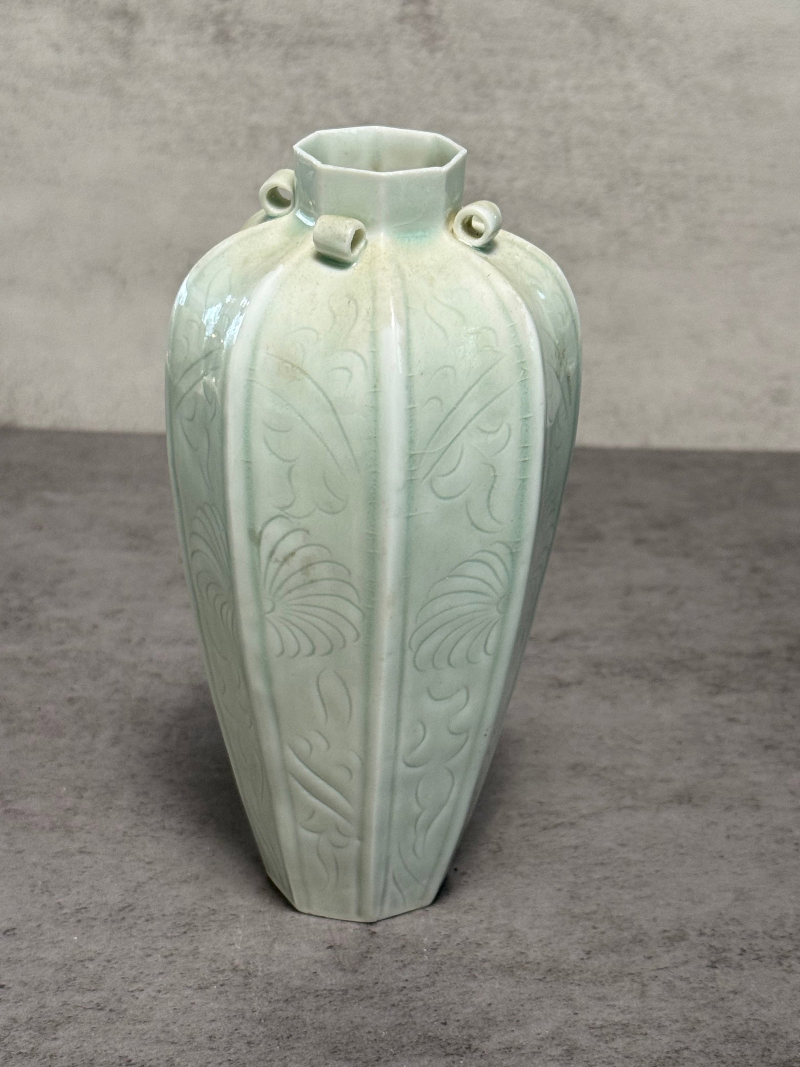 CHINESE CELADON GLAZED HEXAGONAL VASE: A Chinese celadon glazed porcelain vase of elongated hexagonal form, featuring lightly incised foliate and fan-form decoration beneath a pale celadon glaze. The vessel is further accented with small