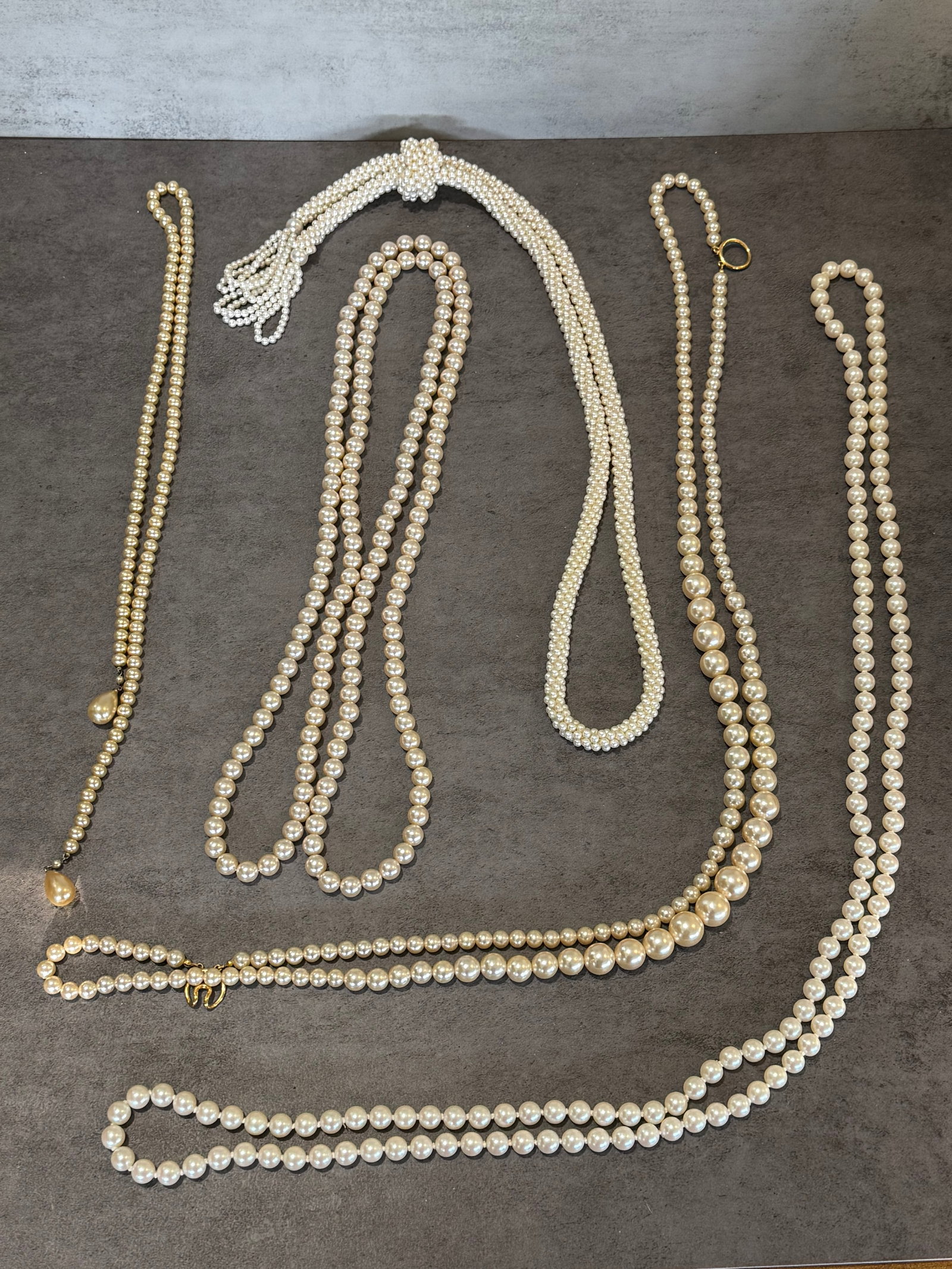 GROUP OF COSTUME PEARL BEAD NECKLACES: A group of assorted costume pearl bead necklaces in varying lengths and styles, including single and multi-strand examples with graduated beads, decorative clasps, and tassel accents. The collection