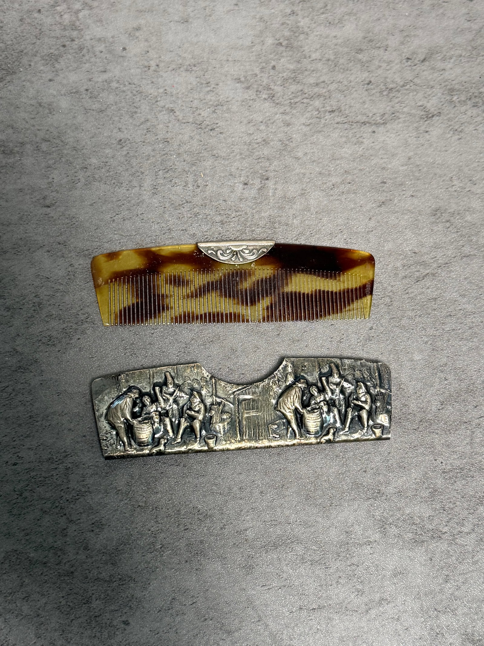 CELLULOID COMB & METAL MATCH HOLDER: A small group including a vintage faux tortoiseshell style comb with decorative metal mount, together with a cast metal match holder featuring figural relief scenes of workers in an interior setting.