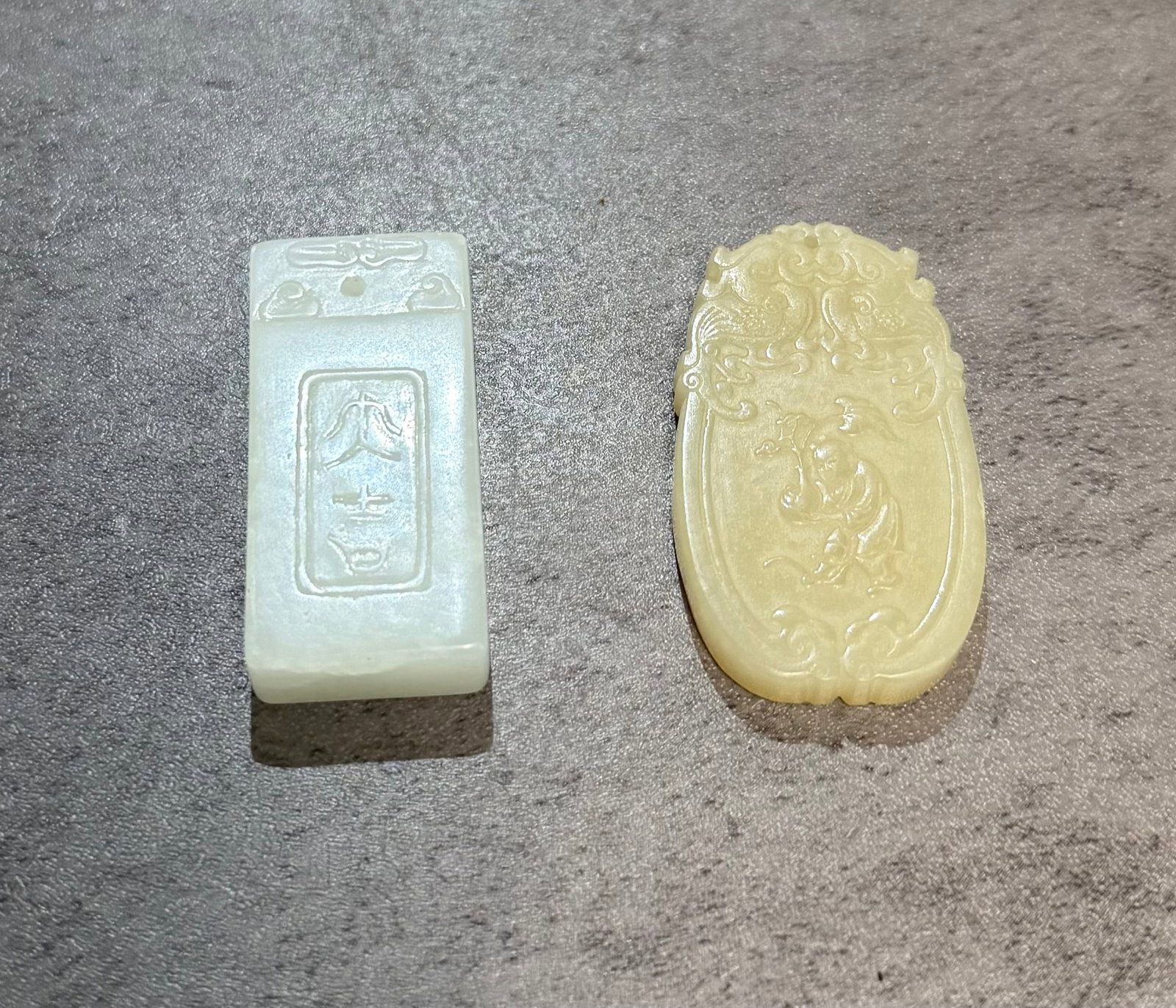 LOT OF TWO CHINESE CARVED JADE PENDANTS: Group of two Chinese carved jade pendants. One in rectangular tablet form carved with stylized characters and archaic inspired motifs, the other carved in pale celadon jade with scrolling decoration