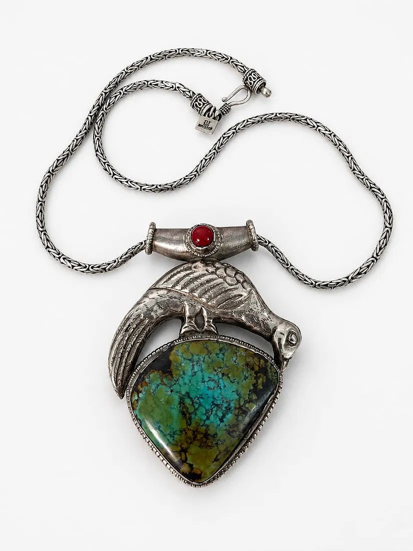 VINTAGE TIBETAN 925 STERLING SILVER TURQUOISE BIRD PENDANT NECKLACE: A substantial Tibetan-style 925 sterling silver pendant necklace featuring a large polished turquoise stone with prominent natural matrix, surmounted by a finely worked silver bird motif. The pendant 