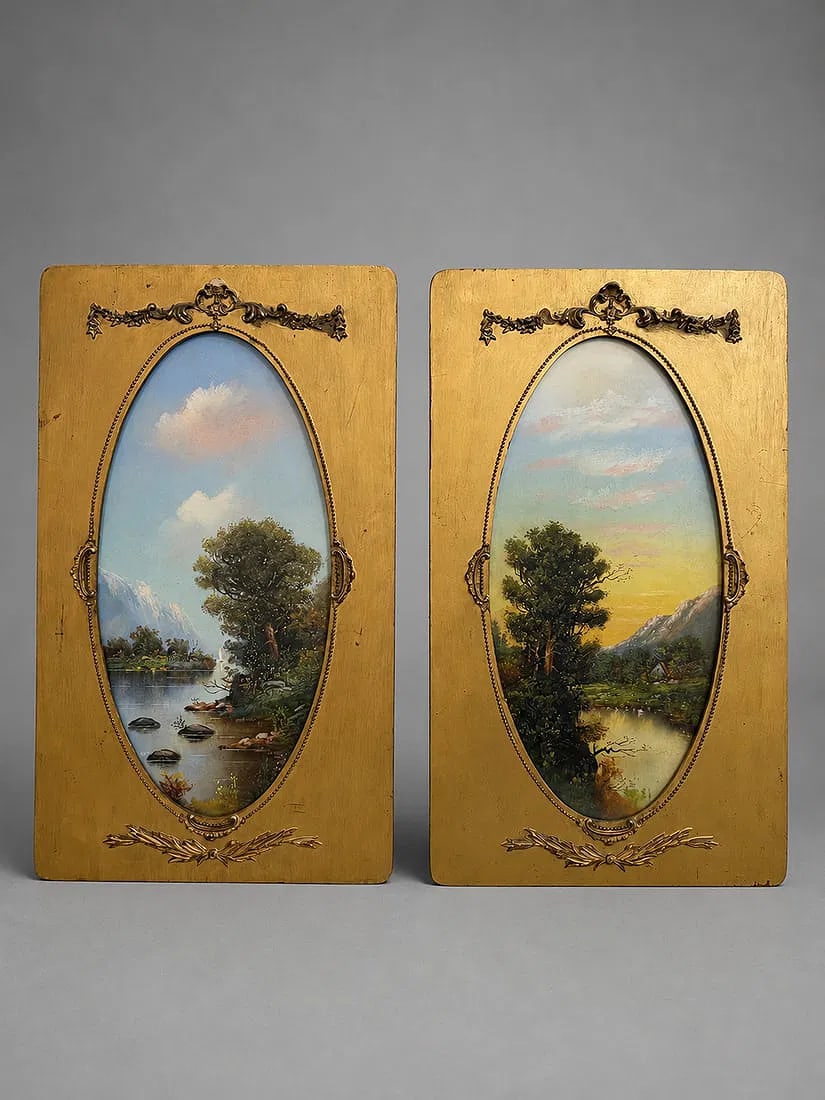 Pair of Hand-Painted Landscape Panels in Gilt Louis XVI Style Frames: A decorative pair of hand-painted landscape panels featuring tranquil lakeside scenes with trees, mountains, and soft pastel skies. Each oval composition is finely executed and mounted within an elega