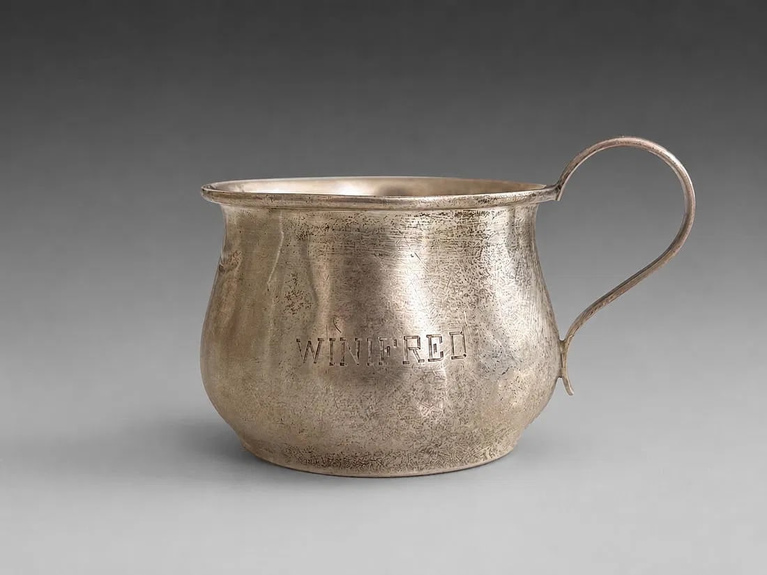 Vintage Sterling Silver Creamer with Personalized Engraving: A vintage sterling silver creamer featuring a classic rounded body with a rolled rim and a simple loop handle. The front is engraved "WINIFRED," adding a personalized touch and period character. Its c