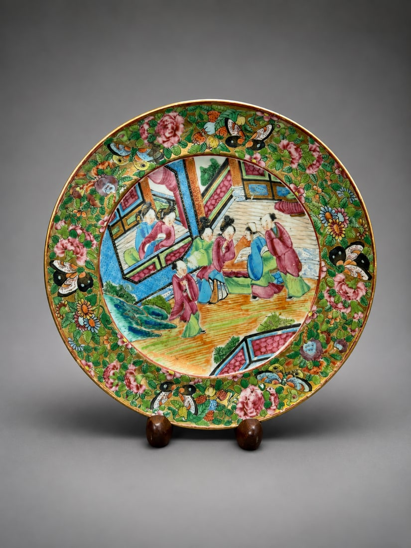 Chinese Famille Rose Medallion Porcelain Plate: A Chinese famille rose porcelain plate decorated in the Medallion style, featuring a central figural courtyard scene surrounded by densely painted floral, butterfly, and foliate decoration in vibrant 