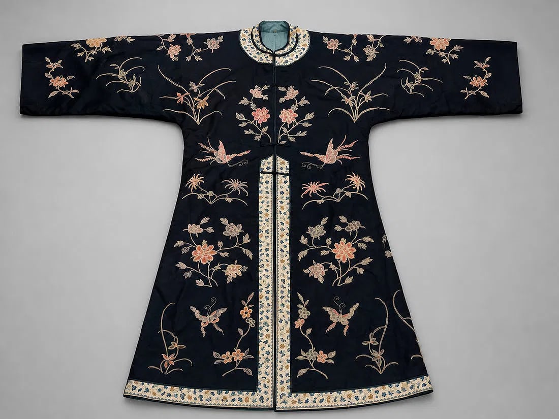 Chinese Embroidered Silk Woman's Robe: A finely embroidered Chinese silk woman's robe featuring an elegant dark blue ground adorned with beautifully executed floral sprays, butterflies, birds, and auspicious botanical motifs. The robe is