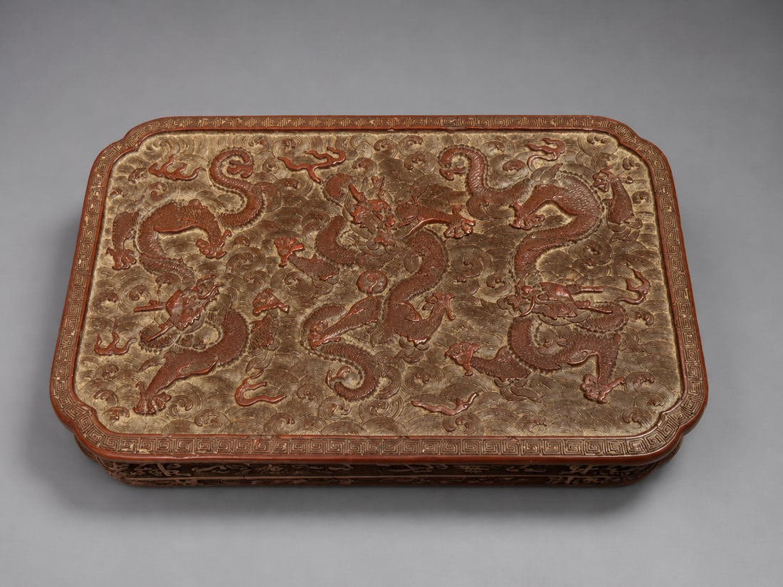 Chinese Carved Dragon Decorated Rectangular Box: A Chinese rectangular box decorated in relief with multiple five-clawed dragons amid dense scrolling clouds, enclosed by a repeating key-fret border. The reddish-brown dragon decoration contrasts with