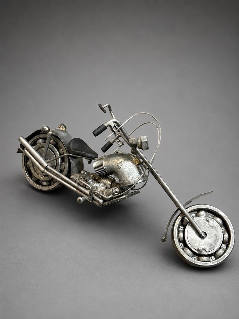 Vintage Handcrafted Metal Chopper Motorcycle Sculpture: A vintage-style handcrafted metal motorcycle sculpture modeled as a classic custom chopper, featuring an elongated front fork, detailed wheels, handlebars, seat, exhaust pipes, and exposed engine comp