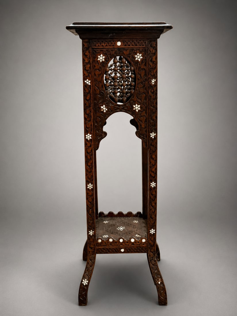 Antique Carved Wood Pedestal Stand with Inlay: An antique carved wood pedestal stand featuring elaborate scrolling and floral decoration throughout, accented with contrasting geometric and floral inlay. The upper section incorporates an openwork p