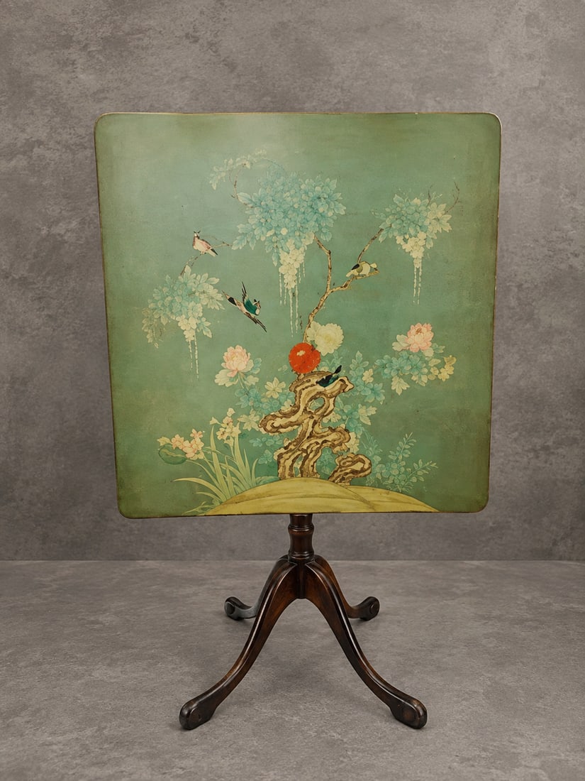 Asian Style Painted Floral and Bird Tilt-Top Table: A decorative tilt-top occasional table featuring a painted panel with birds, flowering branches, blossoms, foliage and scholar’s rock decoration against a green ground. Raised on a dark wood pedesta