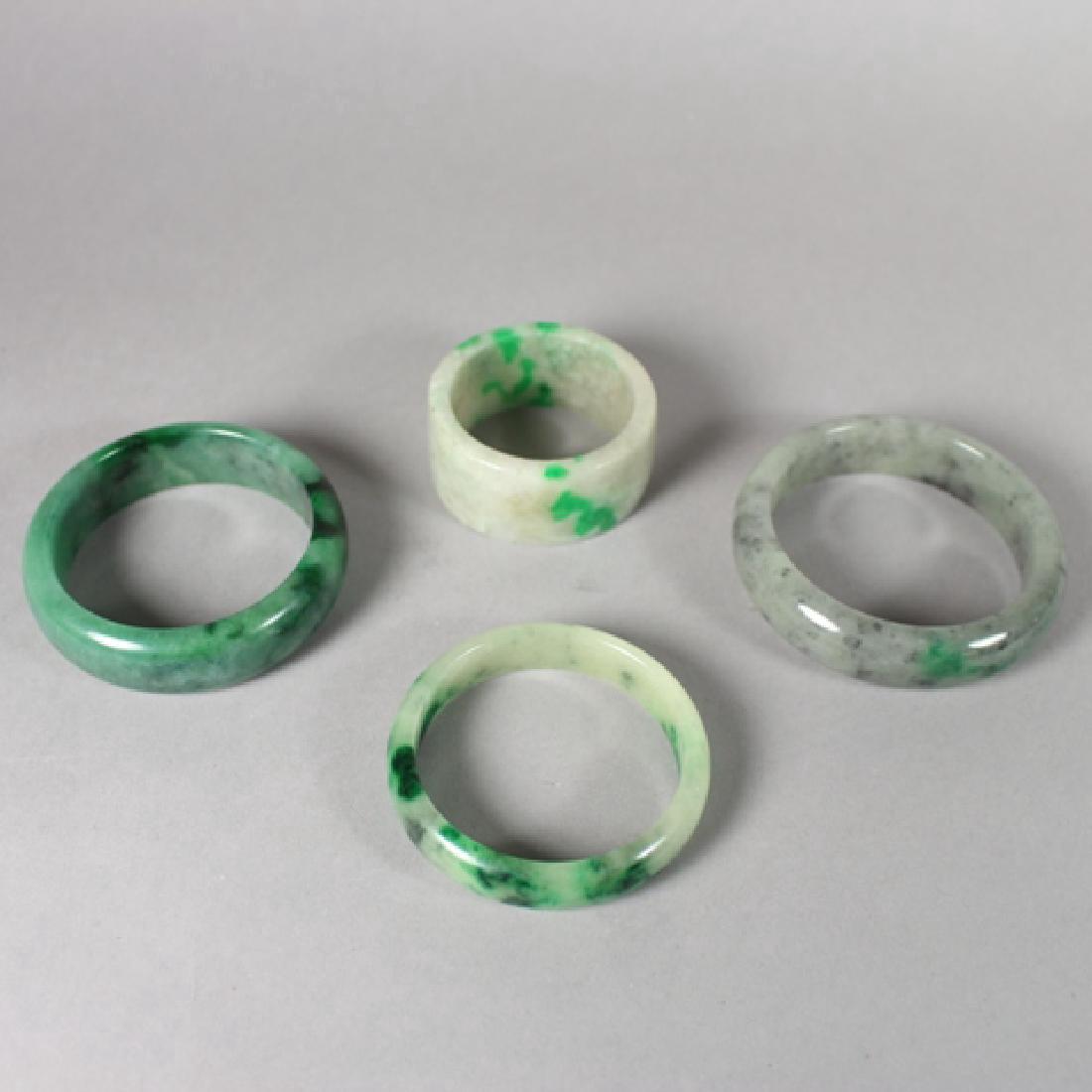 Three 20th Century Jade Bangles and Napkin Ring: Earth tone jade bangle, W. 3.25". Mixed emerald jade bangle, W. 3". White mixed jade bangle, W. 2.75".