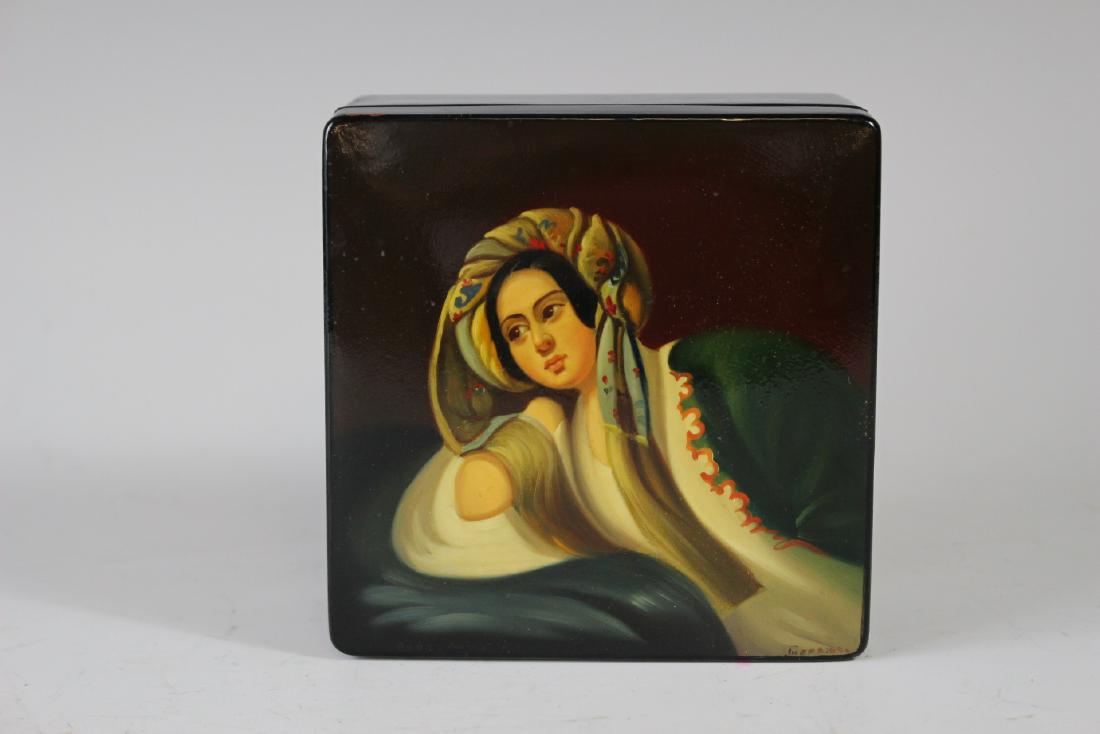 Fine Russian Hand Painted Box: Very fine hand painted and signed front right corner Russian black lacquered portrait of young women seated in laying position. Approx. 4.5" w x 4.5" x 2" tall . Hinged with a red interior. Very good 