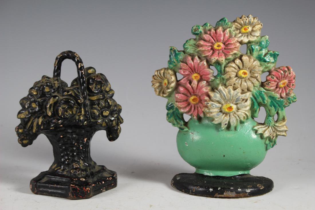 Two Small Cast Iron Floral Door Stops: Two flower basket cast iron doorstops. Tallest is approx. 7" tall. Used condition as shown with some losses. See photos.