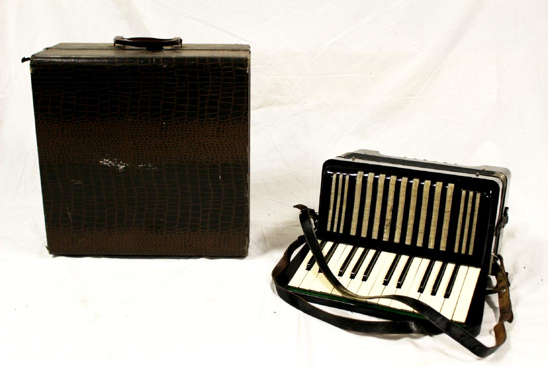 Vintage Hohner Student II Accordion: A vintage high gloss black casing Hohner Student II model accordion. Circa late 1930â€™s, it features a cloth covered speaker with black trim black bellows, and leather straps. Includes hard case