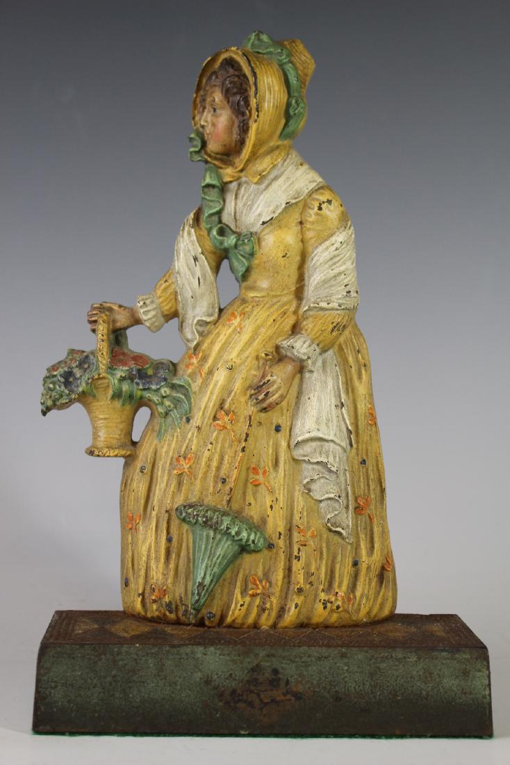 Bradley Hubbard Figural Door Stop: Cast Iron Bradley Hubbard Woman with Flower Basket and Parasol Door Stop. B & H No. 7796, flat backed. Good original condition. 11" tall x 7" w. Light losses to paint and dust soil as shown, see photo