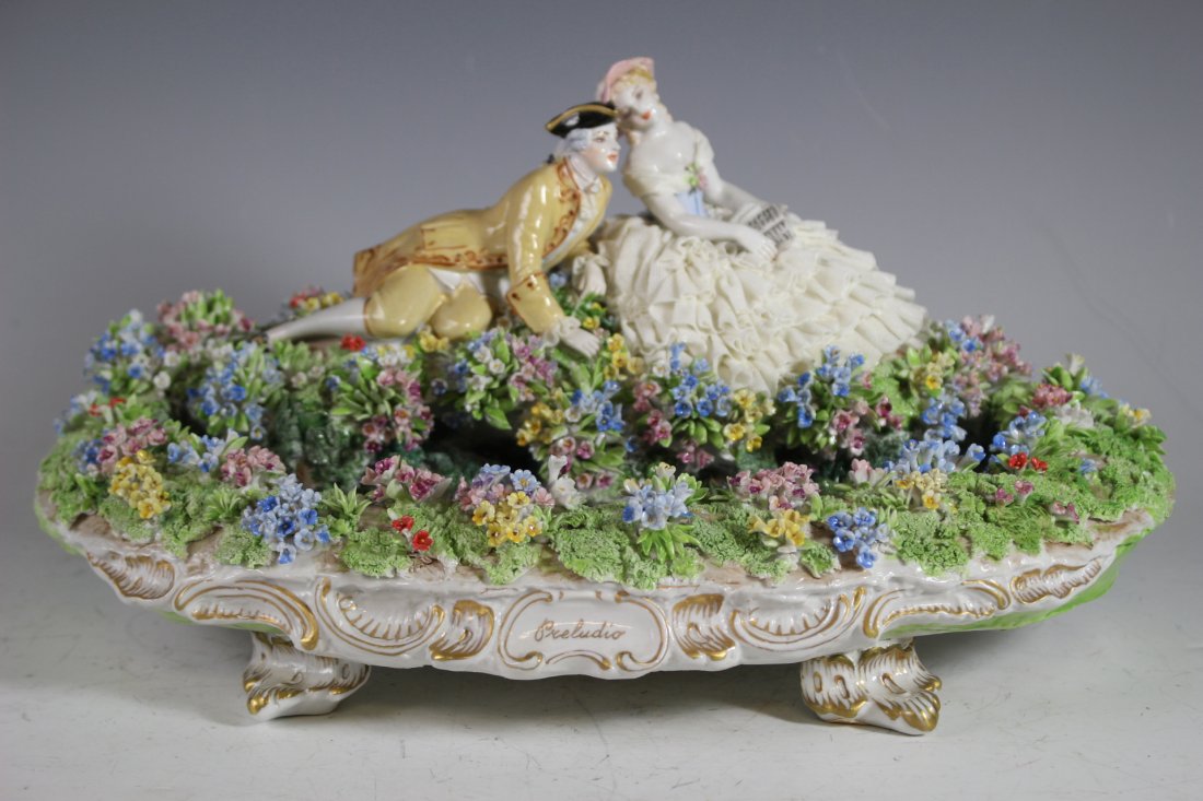 Luigi Fabris Porcalian Group: FONTANA PRELUDIO, showing a man and a woman reclining by a fountain. H: 7" W: 14" D: 10". Some floral losses and chips throughout, see photos for old restoration and repairs on base.
