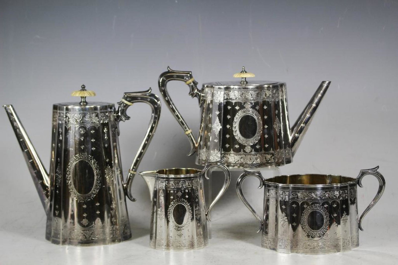 A mid Victorian silver, four piece tea/coffee set by: A mid Victorian silver, four piece tea/coffee set by Elkington & Co, London 1858/59, with bead, floral and scrolled leaf, engraved decoration. Set includes a teapot, a coffee pot, both with ivory