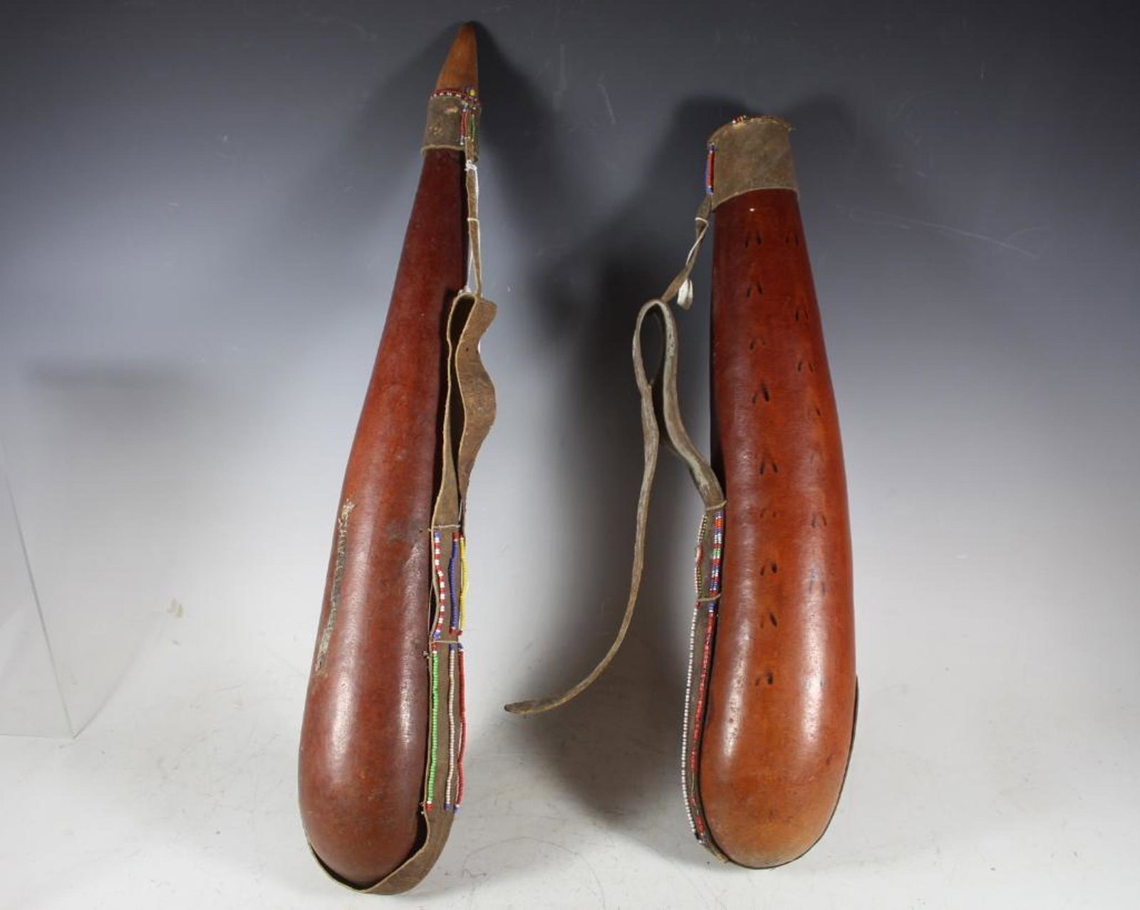 Two West African Yourban Milk Containers: Yourban milk container made of a gourd with trade beads. West Africa. Probably traditional. With leather strap. Length 22" and one 26".Ê Some light signs of use and wear, see photos.