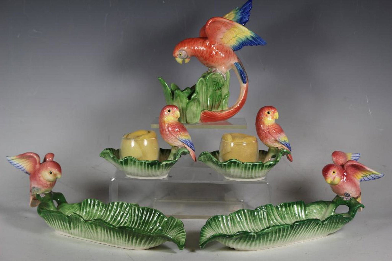 Fitz and Floyd Collection Lot: Group of 1986 vintage Fitz and Floyd parrot Macaw ceramic dishes including two banana leaf serving dishes, a pair of candle dishes with glass never used and a single parrot candle stick.ÃŠ All like