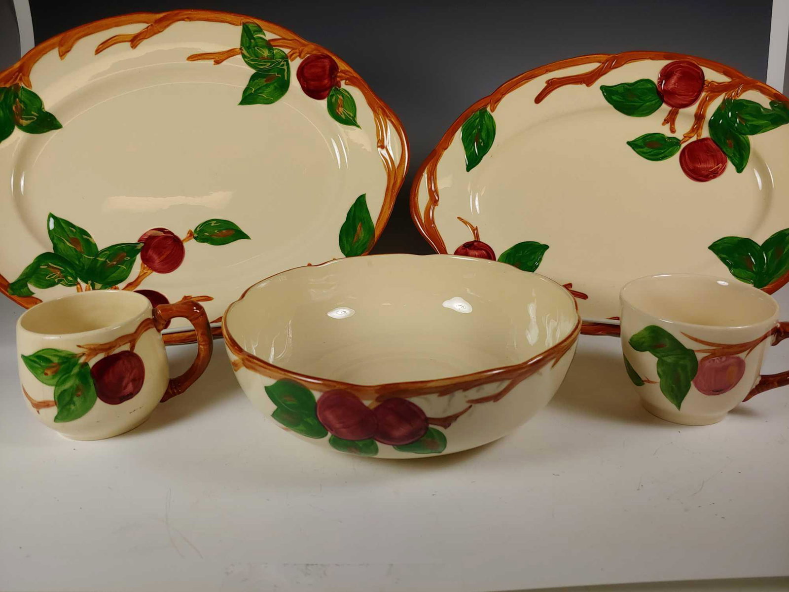 Franciscan Earthenware Apple Pattern Serving Pieces: Franciscan Earthenware Apple Pattern lot includes; 14" serving platter, 12 1/2" serving platter, 8 1/2" vegetable bowl and 2 cups. In good age appropriate condition with large platter having 2 chips t