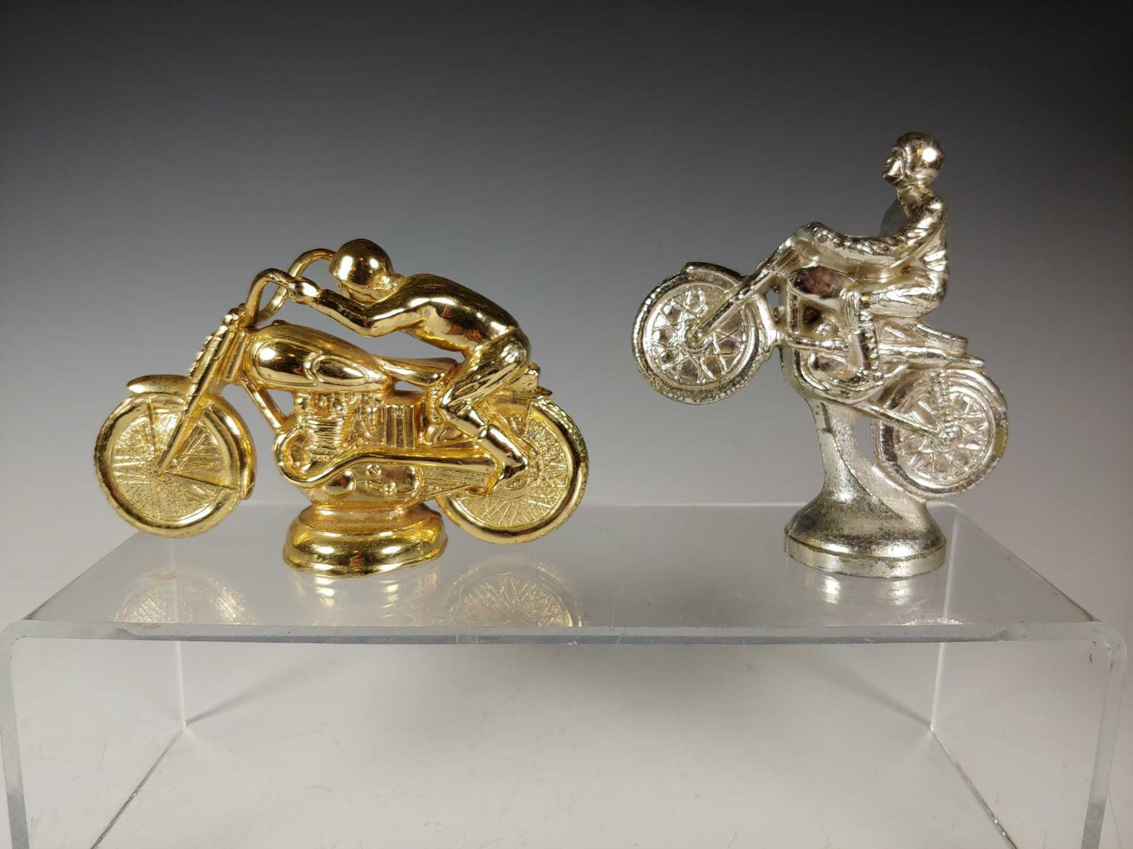 2 Vintage Motorcycle Trophy Tops: Includes; gold racing motorcycle by KAAL solid metal approx. 5" long and silver top by AVNET approx. 4 1/4" tall. Both in age appropriate condition with some minor losses to coatings, see photos.