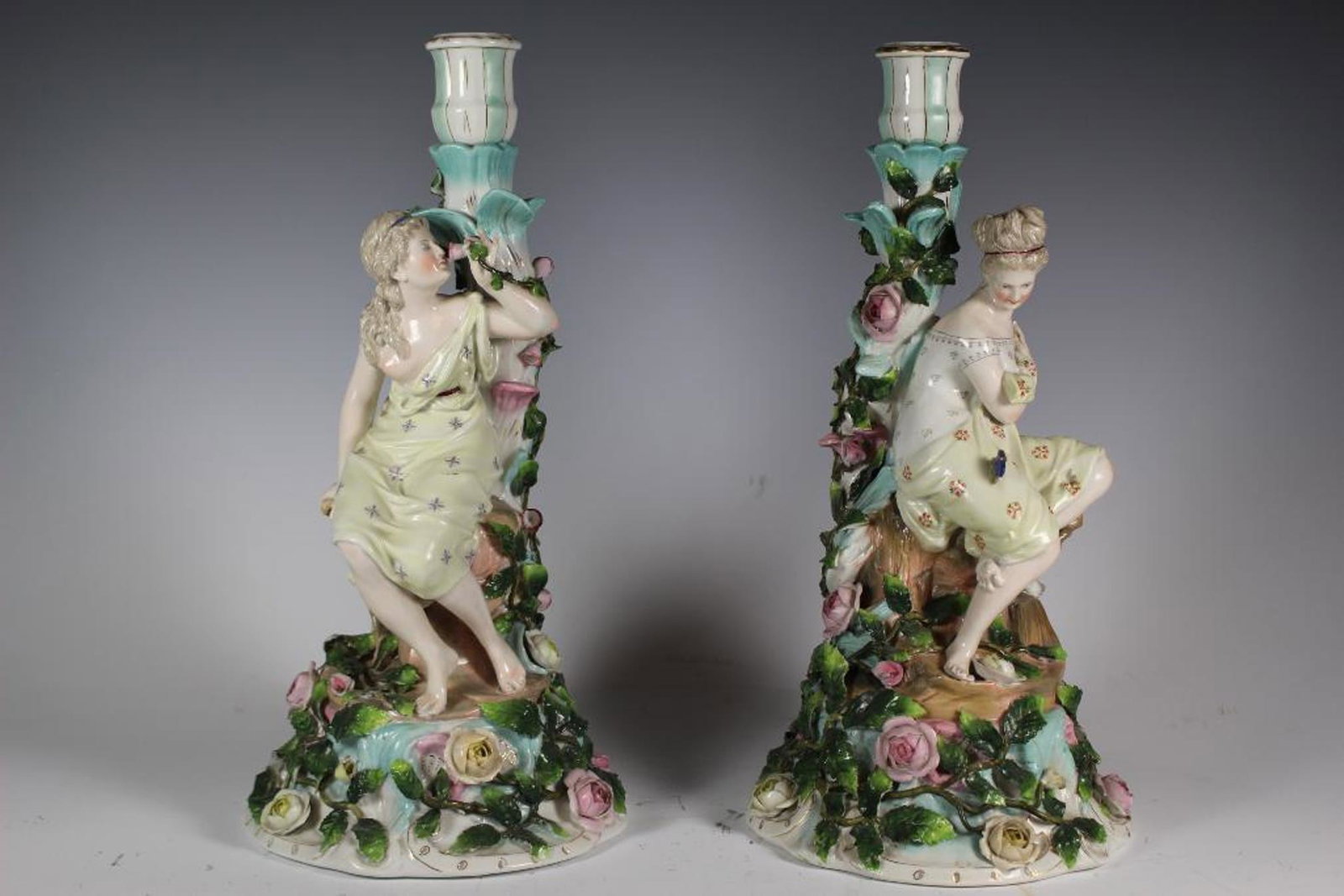 19th. Century Sitzendorf Figural Candlesticks: Wonderful pair of Meissen quality candlesticks depicting seated elegant 19th century woman with one having a blooming caterpillar butterfly and the other smelling the a floral rose. Standing approx 13