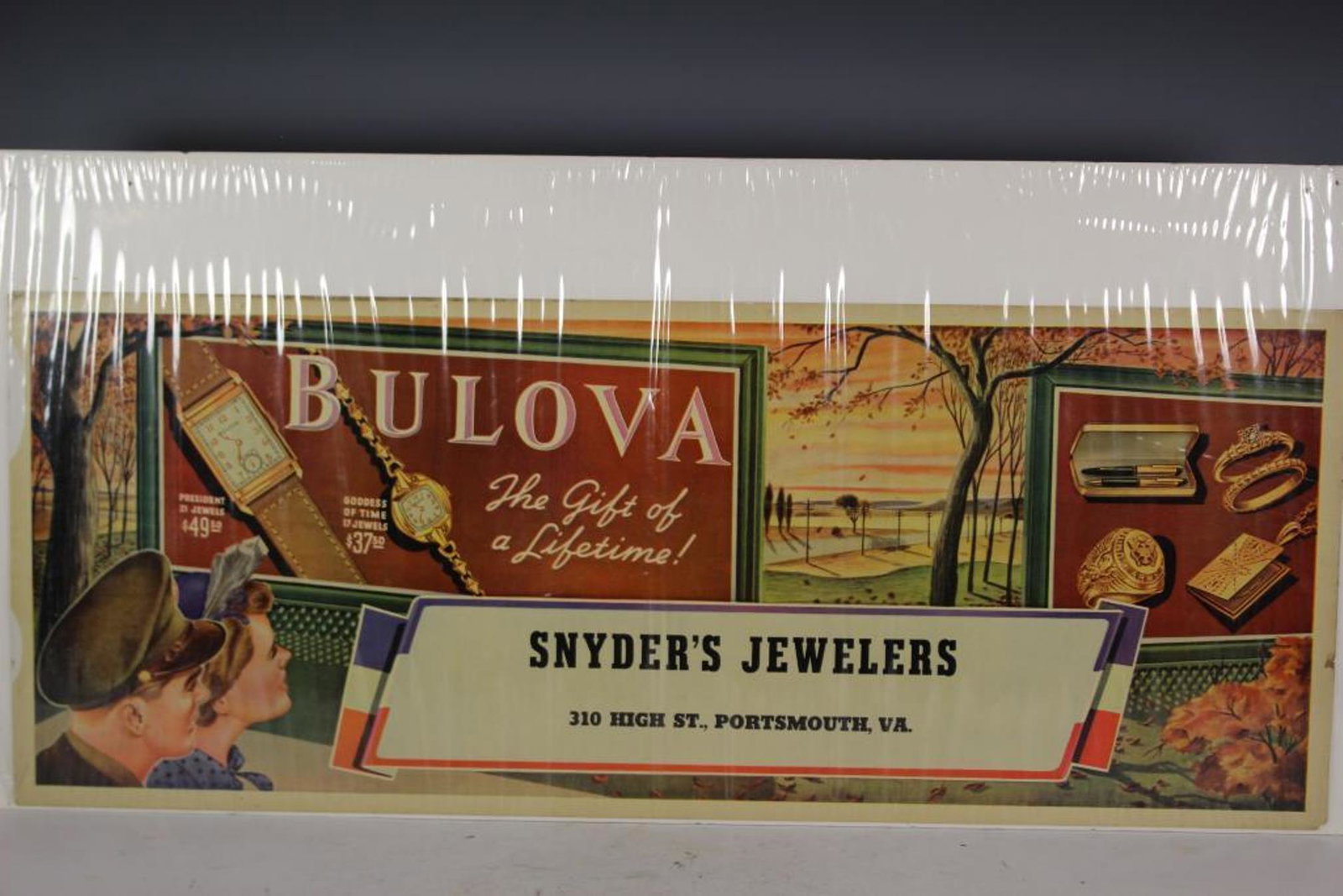 Vintage Bulova Watch Advertising: Vintage Bulova watch jewelry store advertising sign. 28" by 11" cardboard sign reading "Bulova The Gift of a Lifetime" display for Snyder's Jewelers Portsmouth, VA.. Scarce sign not produced in mass q