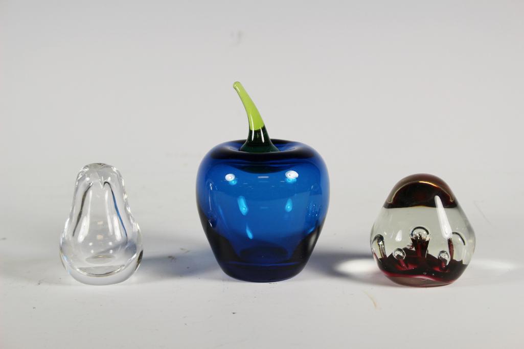Three Art Glass Paperweights: Collection of two art glass paperweights and one perfume bottle missing dabber. Large blue art glass apple Approx. 4 1/4" tall, ruby pear shaped approx 2 1/2" tall and clear pear signed Kosta perfume