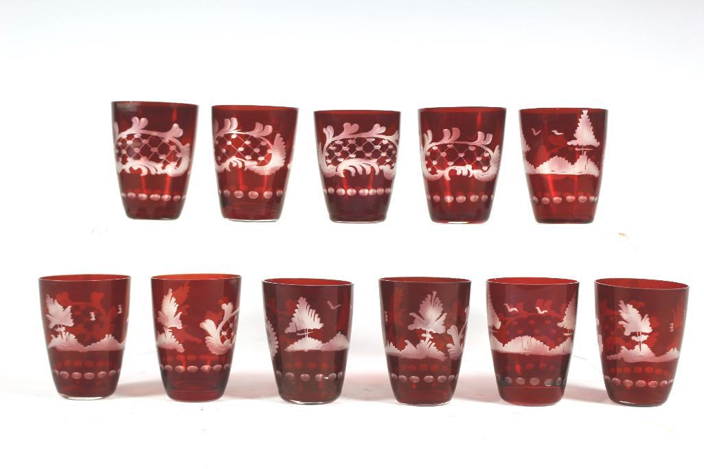 Eleven Bohemia Ruby Etched Glass Shot Glasses: Collection of eleven Bohemia ruby etched to clear glass shot glasses. Approx. 2' tall in good condition with some minor scuffs and one having chip and hairline crack, see photos.