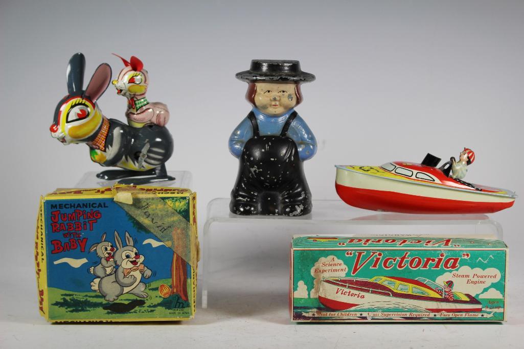 Tin Toy and Coin Bank Lot: Mikuni jumping rabbit with baby tin wind up toy Japan in original box, Schylling Victoria steam powered engine tin boat with original box and Amish coin bank with paint loss, see photos.