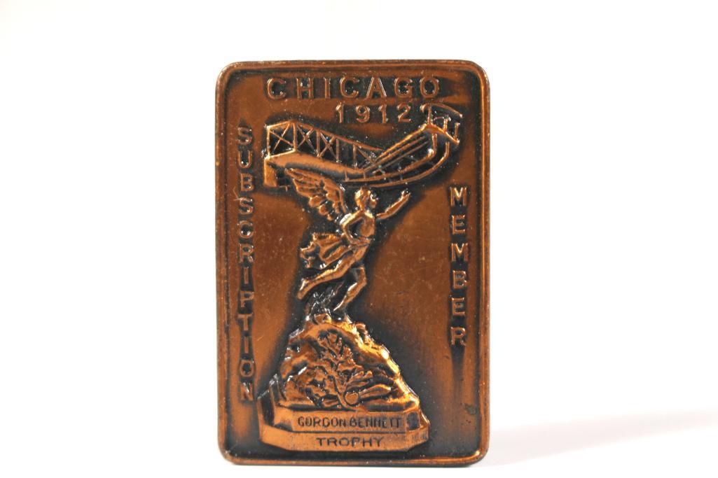 1912 Chicago Airshow Pin-back: Attractive pin-back is 7/8" wide and 1-1/4" tall. Depicts the aviation trophy flanked by the words "Subscription" "Member" "Chicago 1912" This would have been the fourth year this trophy was in existe