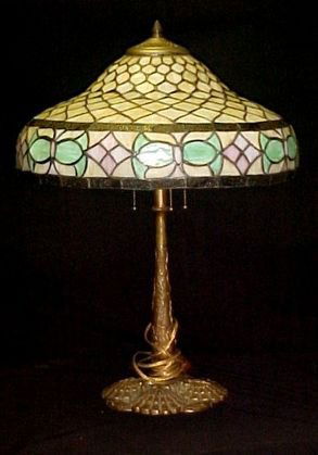 Handel Lamp Base With Leaded Glass Shade: unsigned Handel lamp base with layered shell's and wreath design base and post of foliage. Leaded shade with fish scale design surrounded with pink and green floral border. Condition old minor leading
