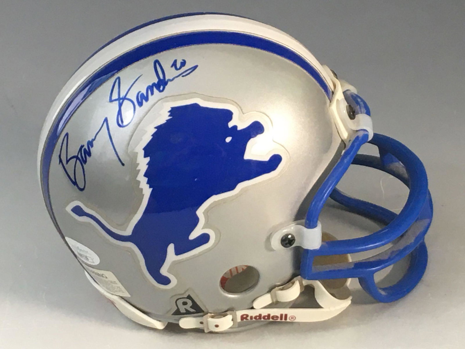 Barry Sanders Autographed Lions Mini-Helmet JSA: Riddell mini-helmet with a early 1990's style facemask. Blue marker signature of one of the best athletes to ever play in Detroit! Shows well with the Lions color scheme. A few scuffs on the helmet. J