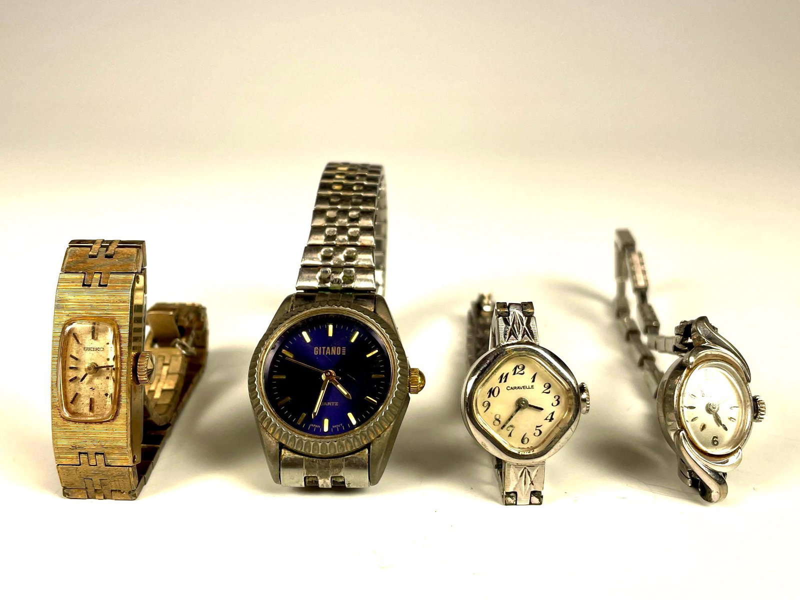 Four Vintage Ladies Wrist Watches: Includes working Bulova with oval bezel/face, Caravelle Diamond faced currently working and two others as shown. See photos. Use and wear throughout