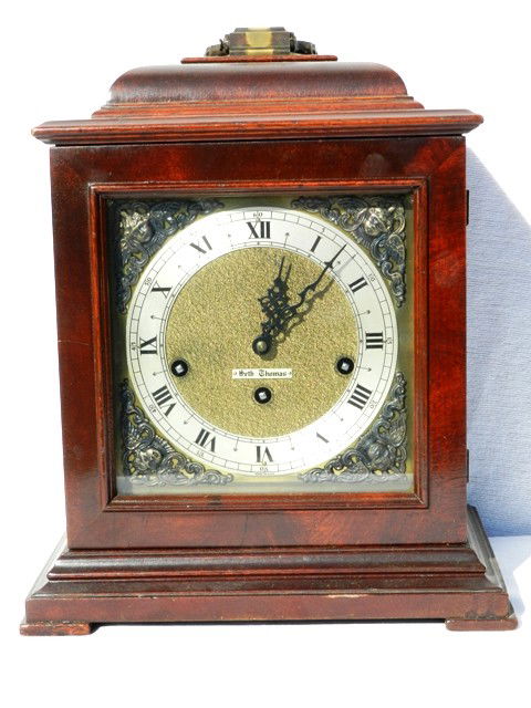 Seth Thomas Shelf Clock In Mahogany Case: With a metal 4 corner cherub face on square feet. Good condition. Approx 14" x 11".
