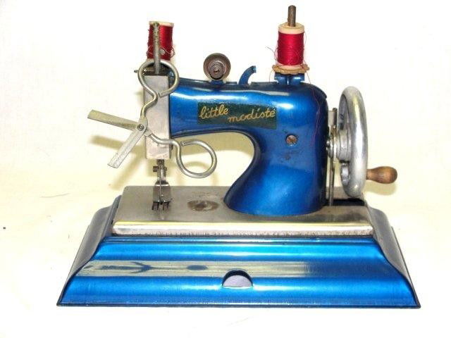 Casige German Toy Vintage Sewing Machine: LITTLE MODISTE ** Great child's toy in a metallic blue color, with original decal label, stamped with the name Casige. I believe this was made for Macys stores. 7 1/2" T. 0 3/4" L.5 1/2" W.