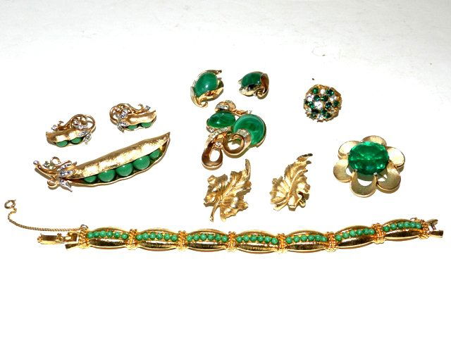8pcs Vintage Trifari Costume Jewelry Lot: Including a 3pc slit pea brooch and earring set decorated with rhinestones, 3pc set Faux Stones decorated with rhinestones, Faux emerald brooch, pair of leaf earring and more. bracelet and ring are on