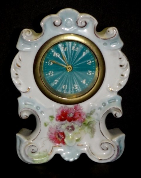 German Porcelain Miniature Dresser Clock: Hand Painted red roses on scalloped Royal Bonn style shaped case, with spun face dial. Condition very good and working. H. 5 1/2'' W. 4'' D. 1 1/2''
