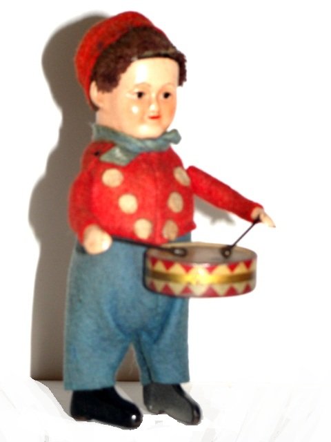 Schuco Windup Drummer Boy Ca. 1930's: When wound, bangs his drum rhythmically. Made from tinplate with painted features, he has a brown mohair head, he wears a red felt two piece and red fez. From a series of figures released in sets by S
